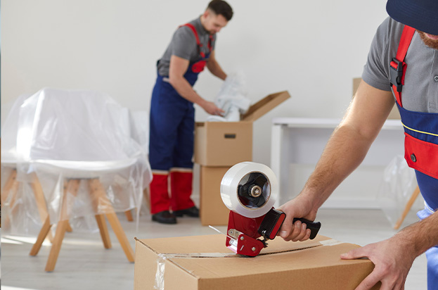 two movers packing boxes with tape in a modern room